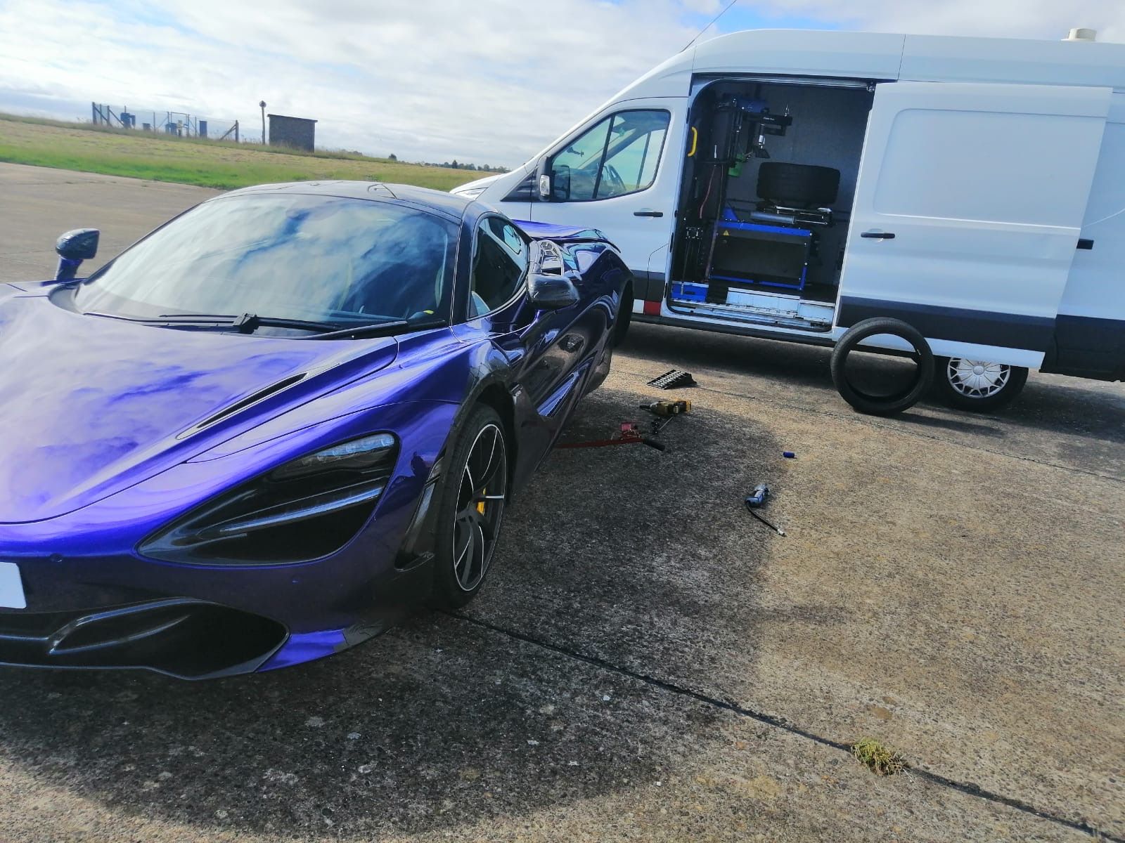 Purple McLaren beside the open Dustcap van on an airfield apron